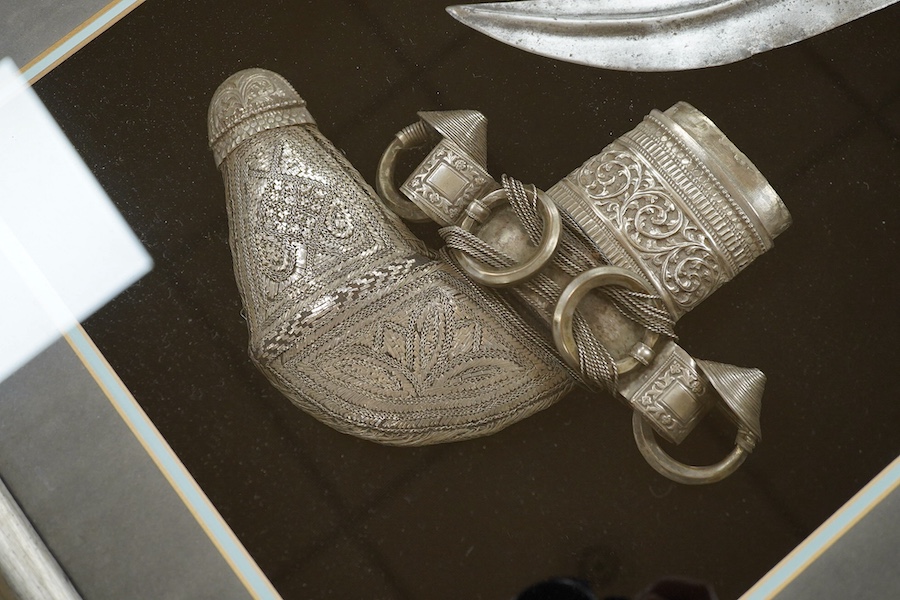 A silver mounted Arab Khanjar dagger from Oman, wooden grip, mounts chased in relief with scrolling foliage, contained in an illuminated display case for wall mounting, 79cm x 58.5cm. Condition - good.